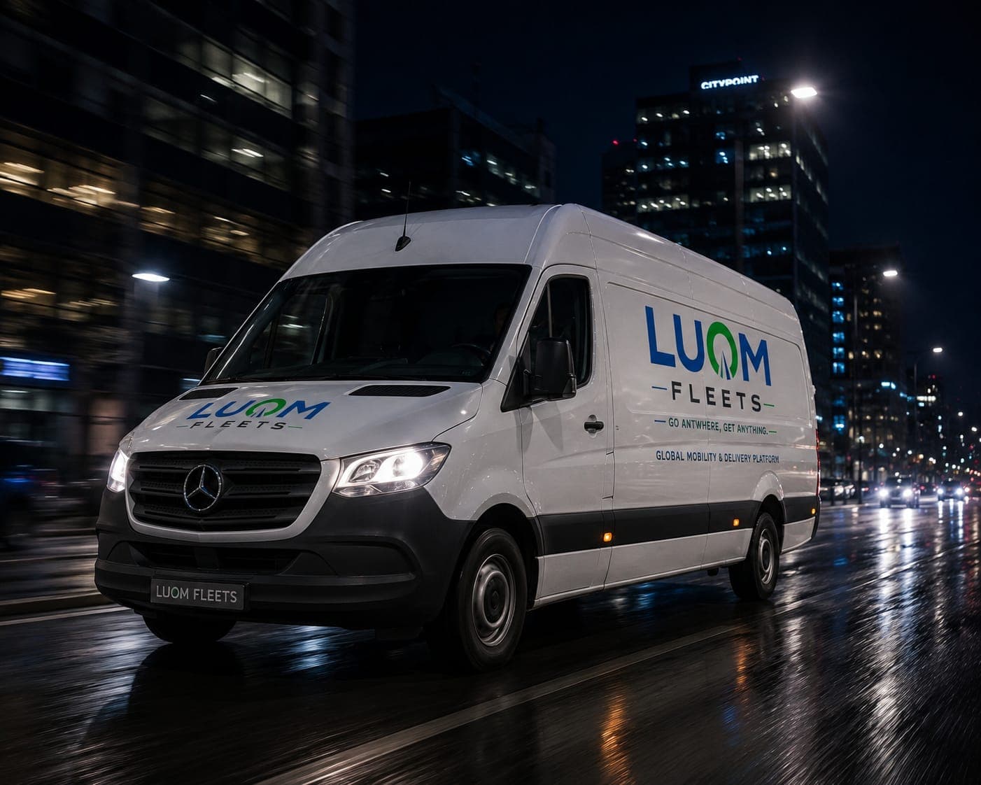 Weißer LUOM FLEETS Mercedes-Transporter fährt nachts auf einer nassen Stadtstraße an hellen Gebäuden vorbei.